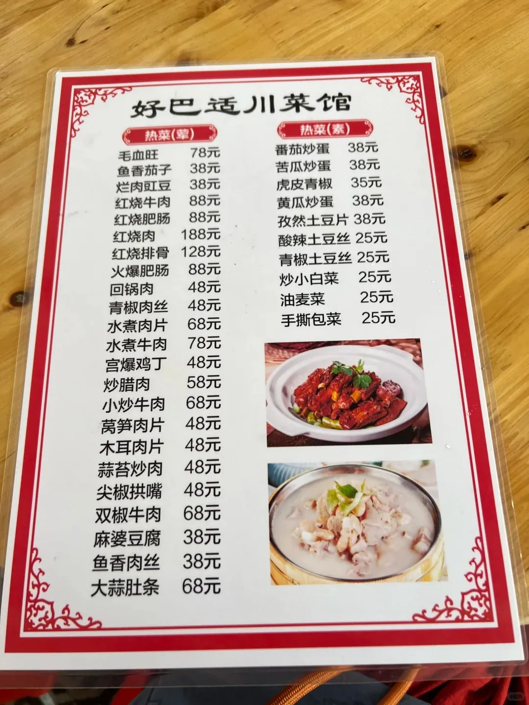 A laminated menu from a Chinese Sichuan restaurant, displaying two columns of hot dishes with their names in Chinese characters and prices in Yuan. The menu lists both meat and vegetarian options, featuring two small inset photos of prepared dishes like braised meat and a milky soup.