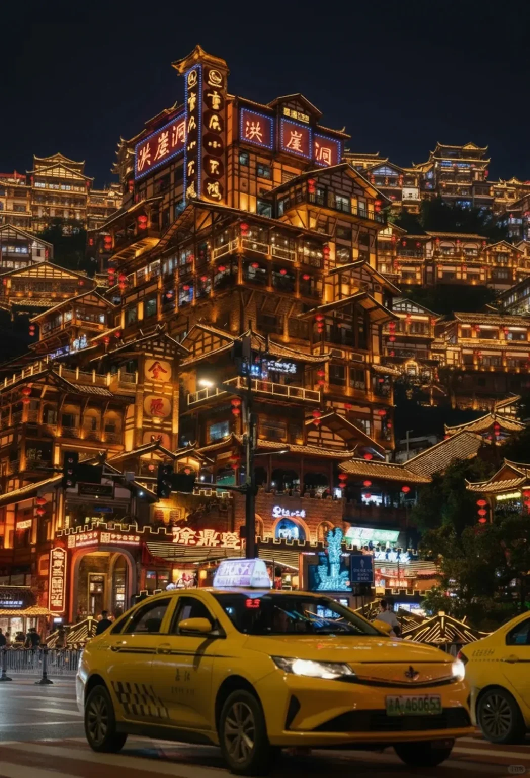 An illuminated night view of the multi-tiered Hongyadong commercial complex in Chongqing, China. Traditional wooden stilt houses, adorned with warm string lights and red lanterns, ascend a hillside, creating a vibrant scene. Neon signs with Chinese characters glow on the building facades. On the street level, yellow taxis are visible, along with people walking.