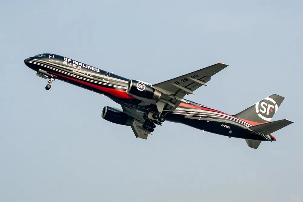 A black SF Airlines cargo plane, registration B-2899, with red and white stripe livery and the SF logo on its tail and engines, is shown in flight against a clear blue sky with its landing gear extended.