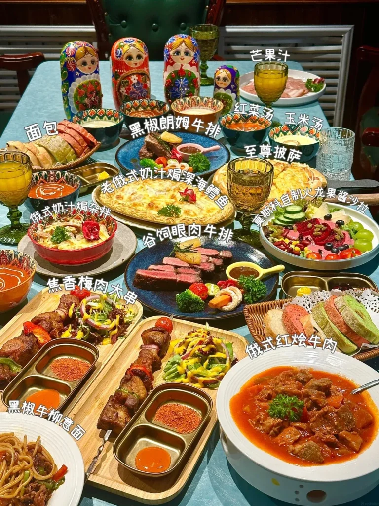A long table laden with various Russian and Russian-influenced dishes, including a large bowl of beef stew in tomato sauce, sliced steak, meat skewers with salad and dipping sauces, a baked dish resembling a large quiche or pie, a salad with beets and blueberries, various types of bread, and small bowls of soup. Russian nesting dolls are visible in the background.